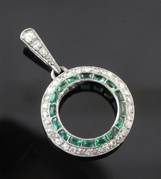 A white gold, emerald and diamond open circular pendant, overall 26mm.